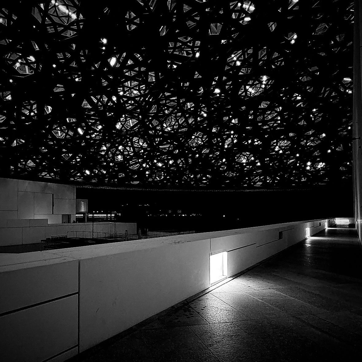 A shaft of sunlight crosses a dark walkway below the patterned dome.