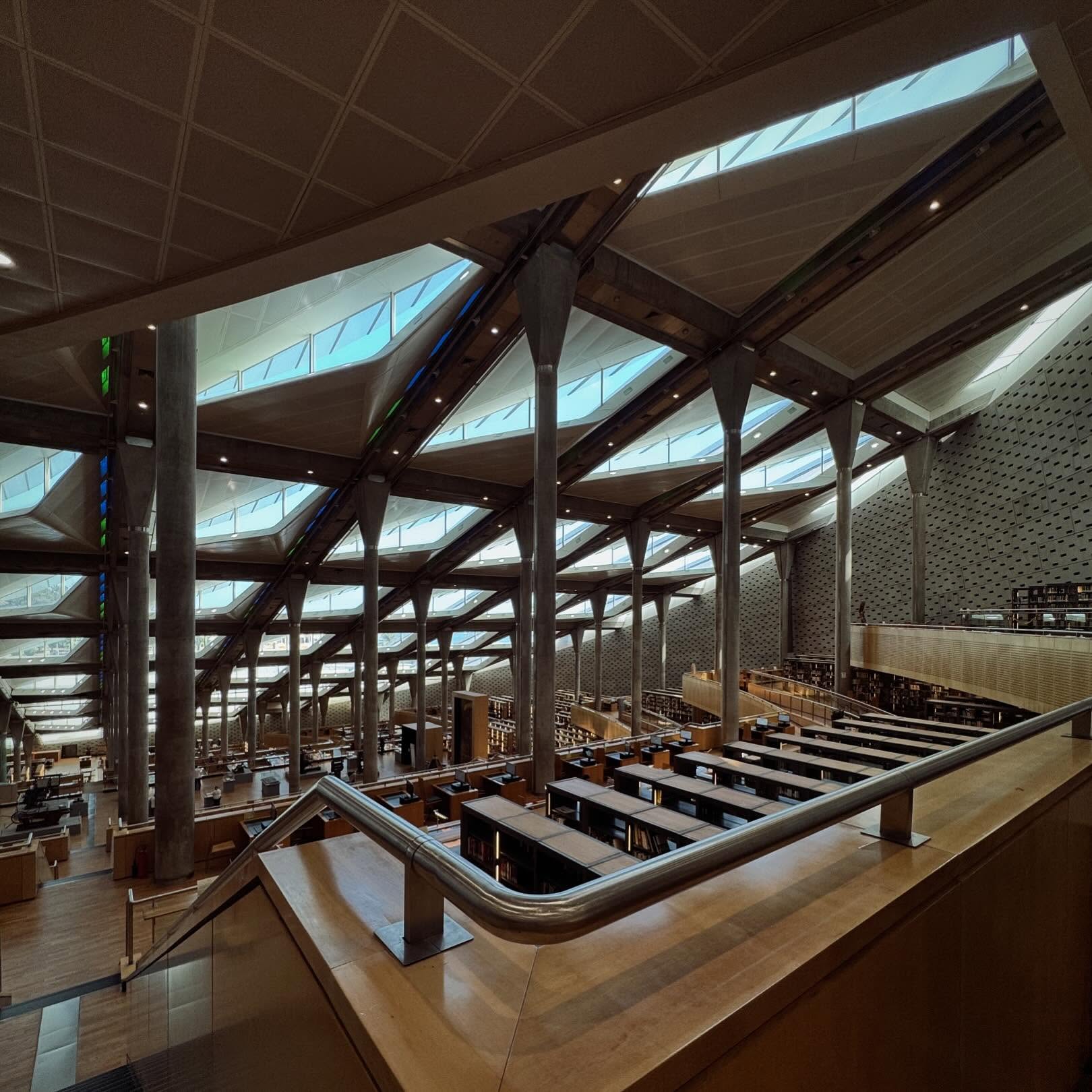 Terraced reading areas beneath the library’s angled roof and tall structural columns.