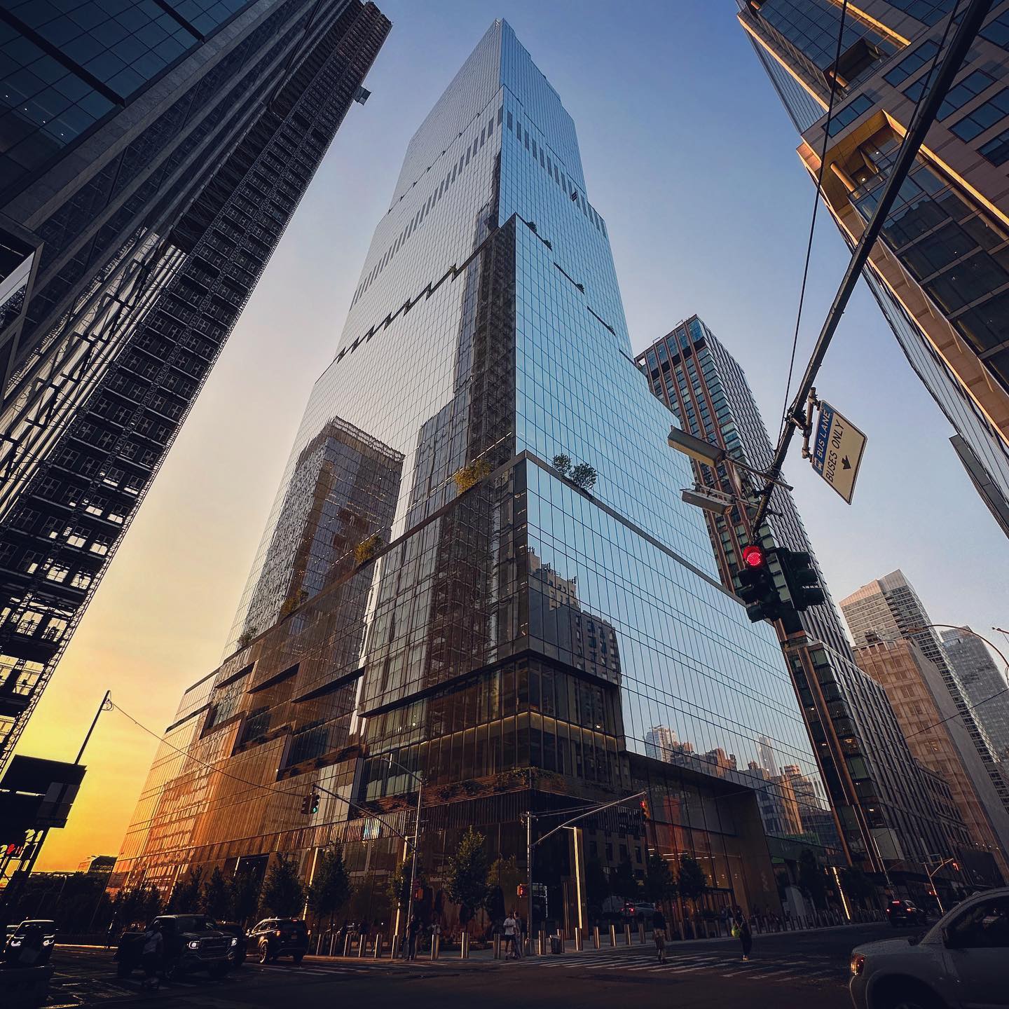 An angular glazed tower catches warm reflections at a street intersection.