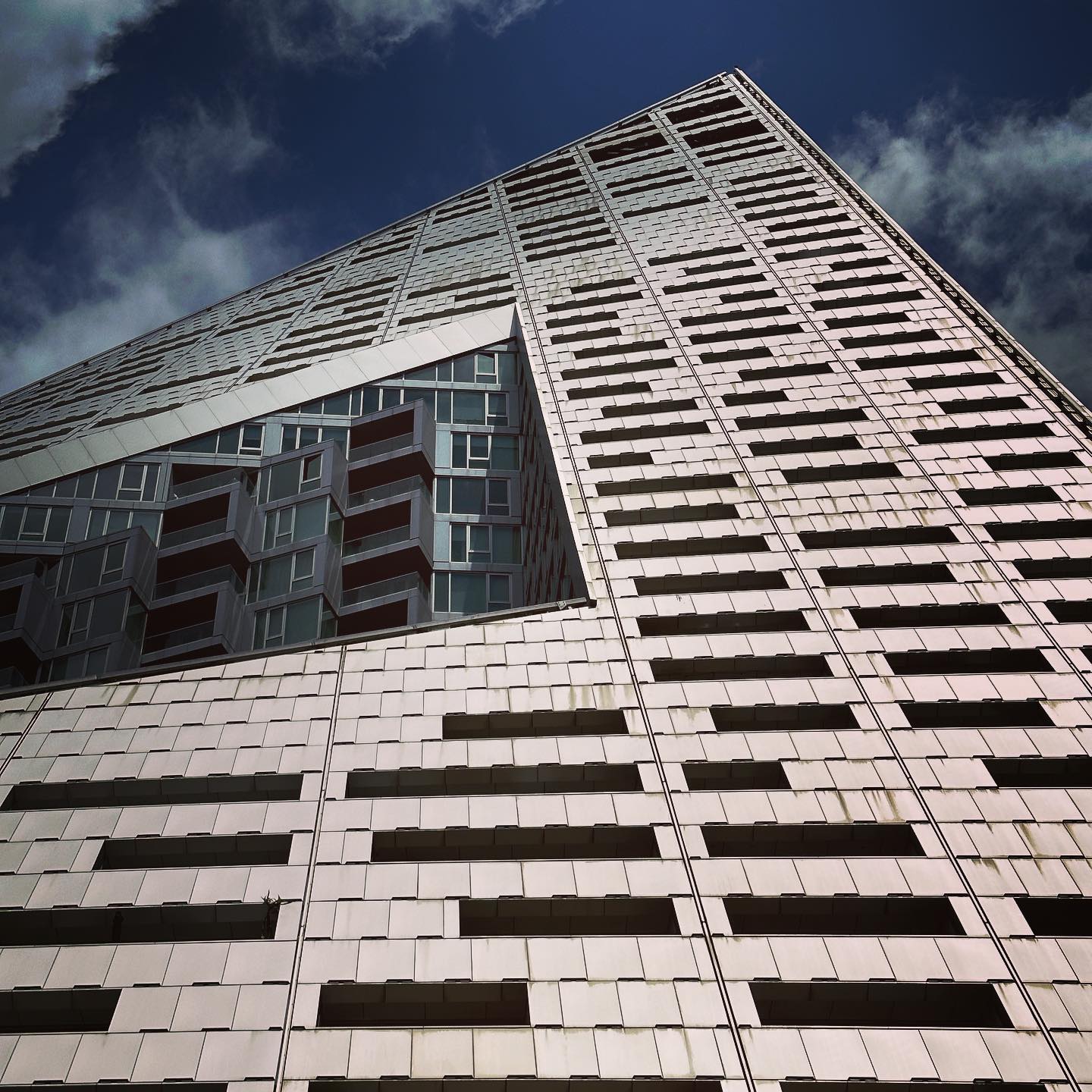 A grid of stone and glazing rises steeply towards a dark blue sky.