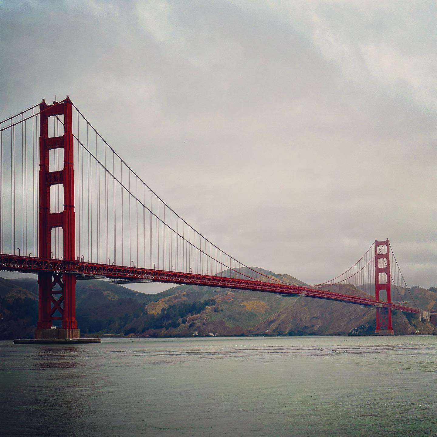 The red bridge towers and suspension cables recede across the water.