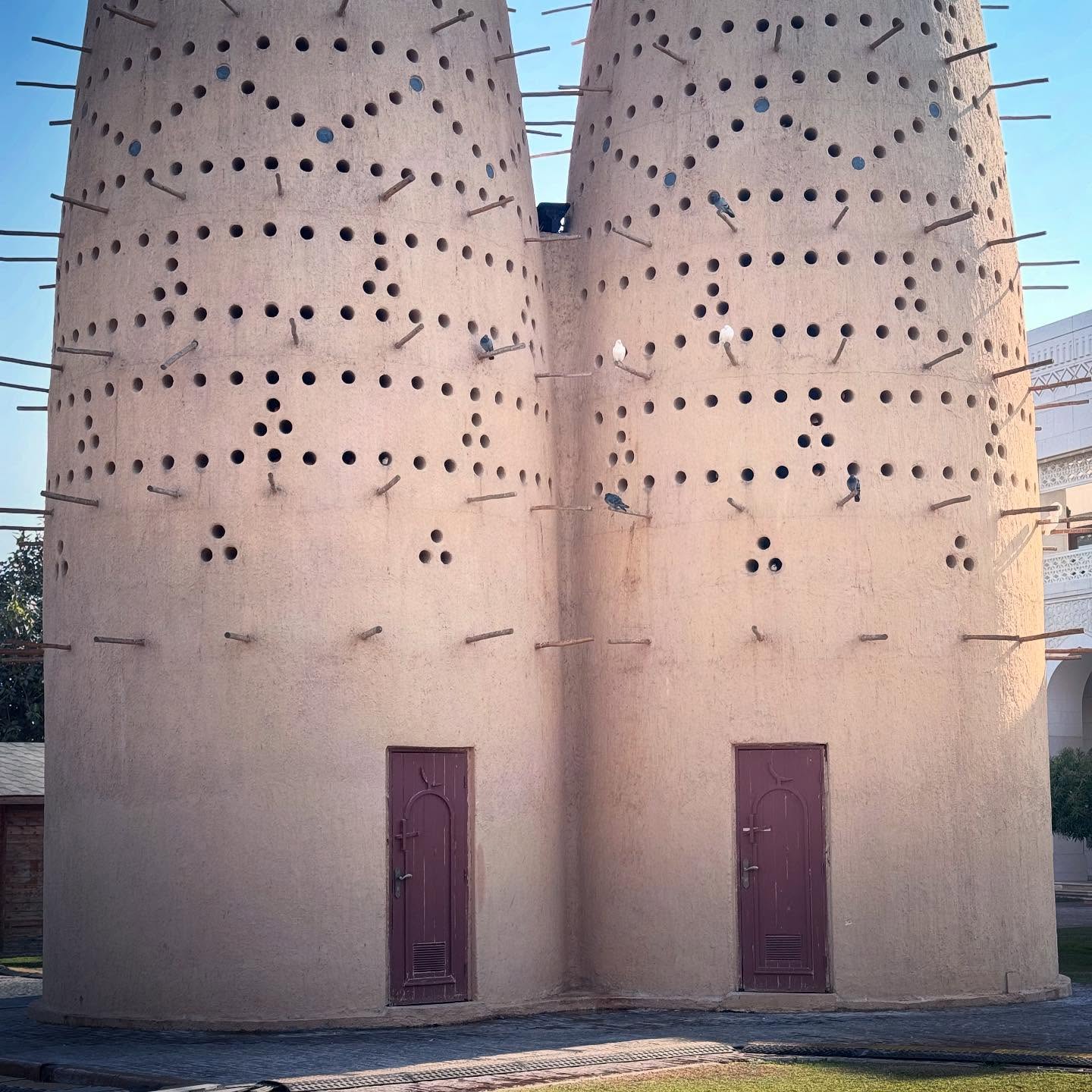 Two pale pigeon towers with patterned openings and small doors.
