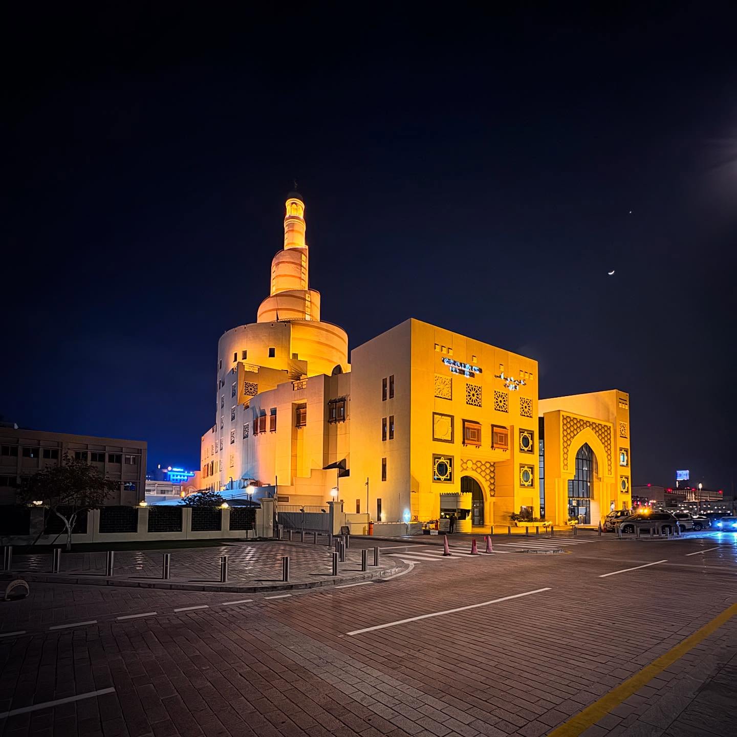 Fanar’s illuminated spiral tower and façades at night.