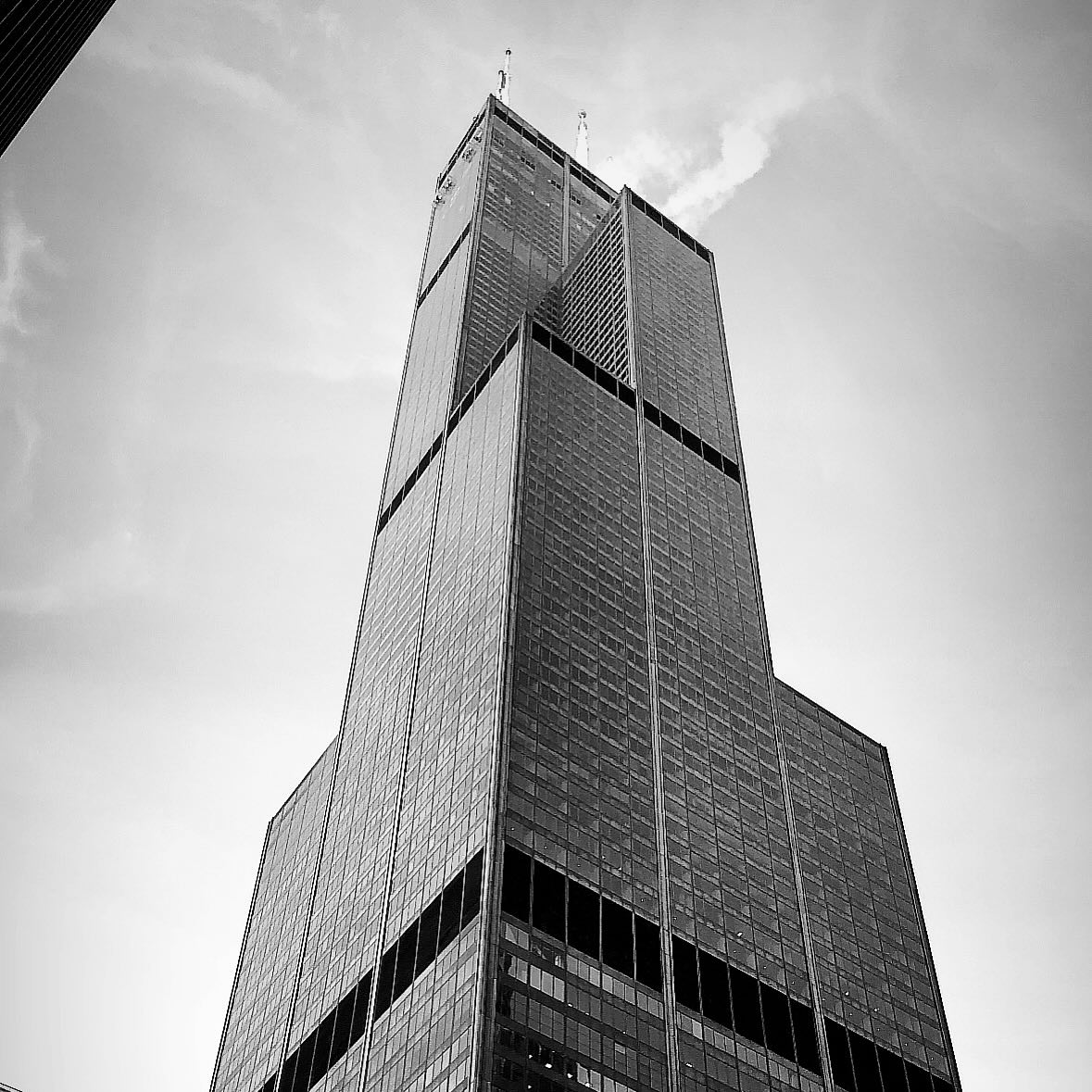 A tall, stepped skyscraper photographed from below in black and white.