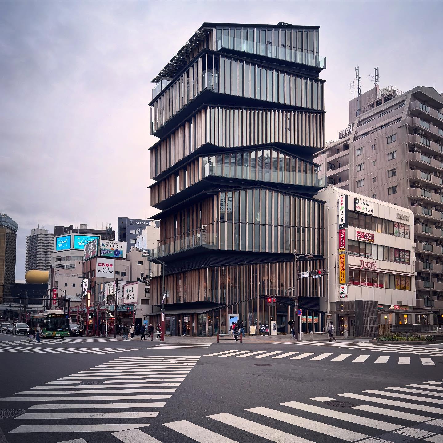 Stacked, screened floors above a busy street corner in Asakusa.