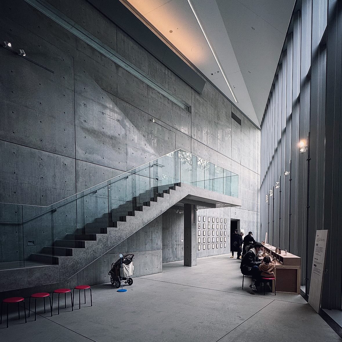 A concrete staircase and tall glazing bringing daylight into 21_21 Design Sight.