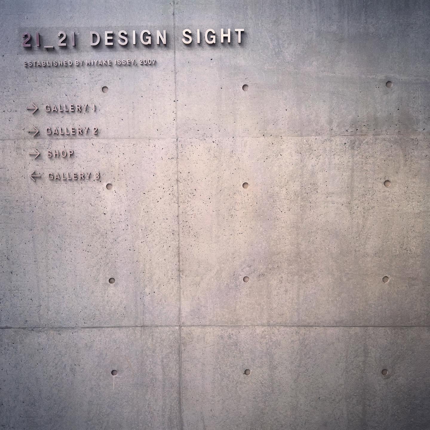 Museum wayfinding lettering set against a textured concrete wall.