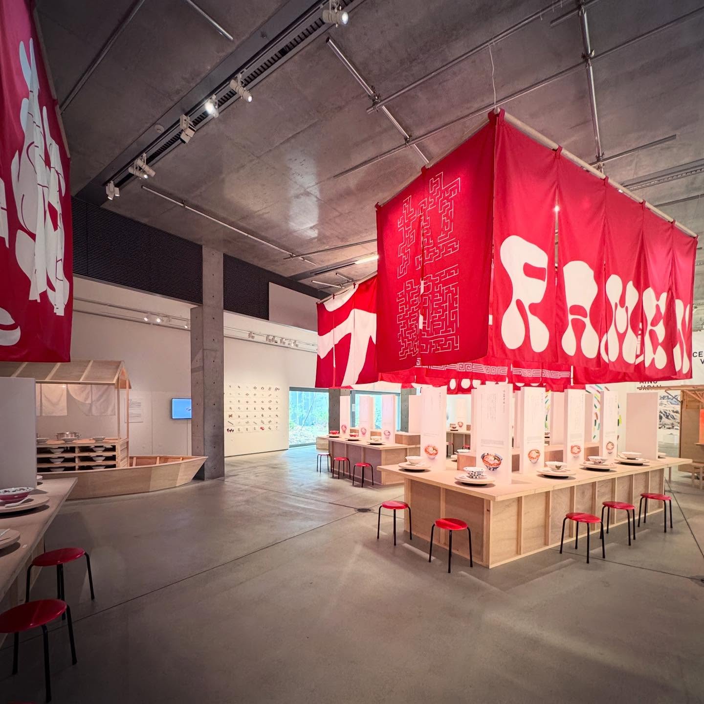 A red exhibition installation beneath the museum’s concrete ceiling.