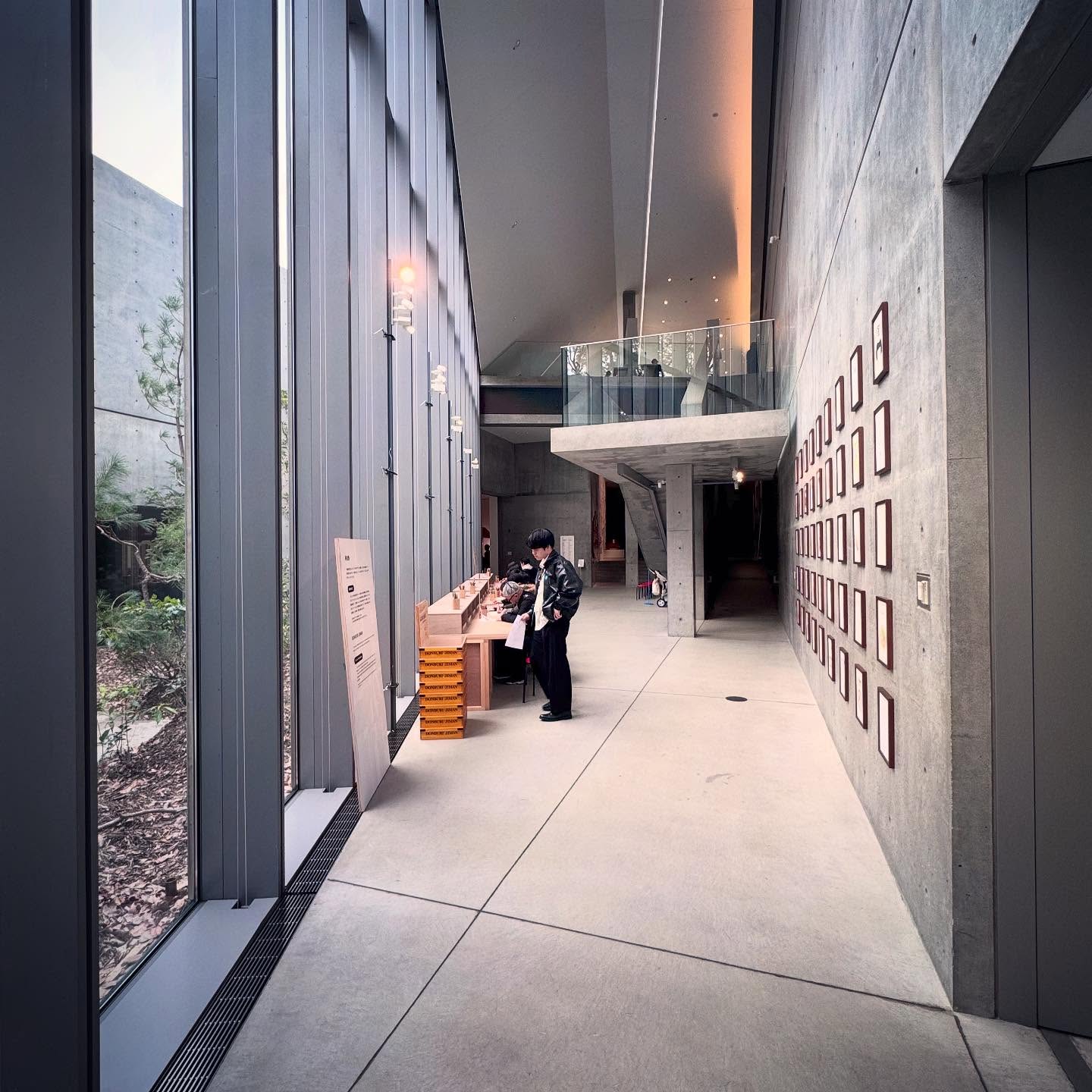 A long passage between tall glazing and a concrete wall.