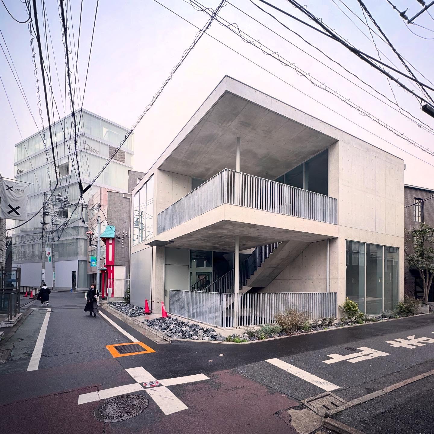 A pale building with open terraces on a small Shibuya street corner.