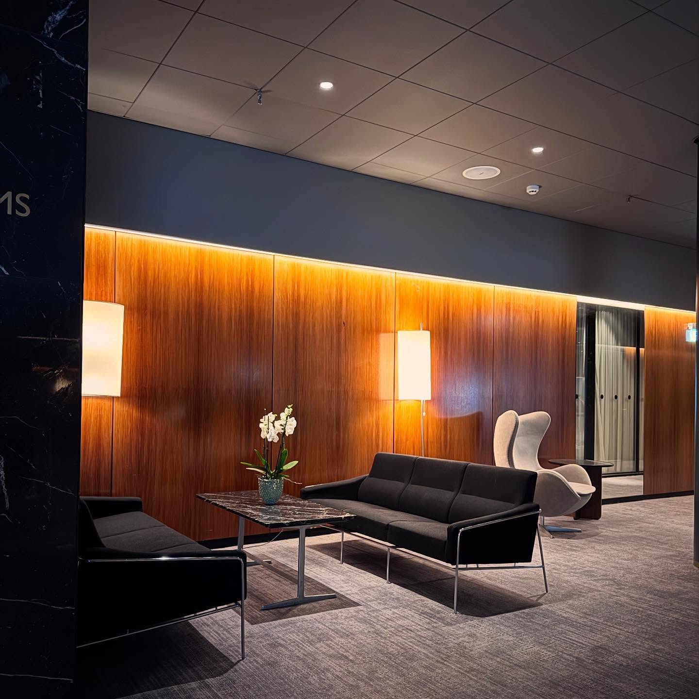 A quiet seating area against a backlit timber wall.