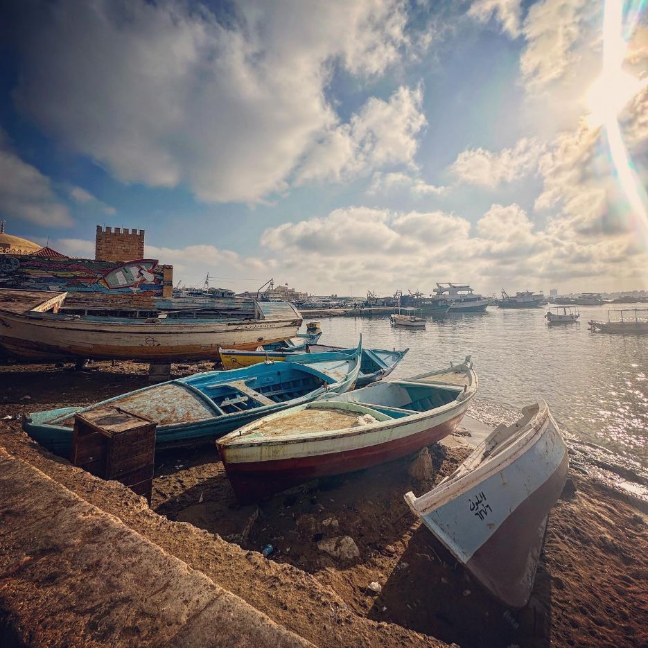 Fishing boats along Alexandria’s waterfront beneath a dramatic sky.