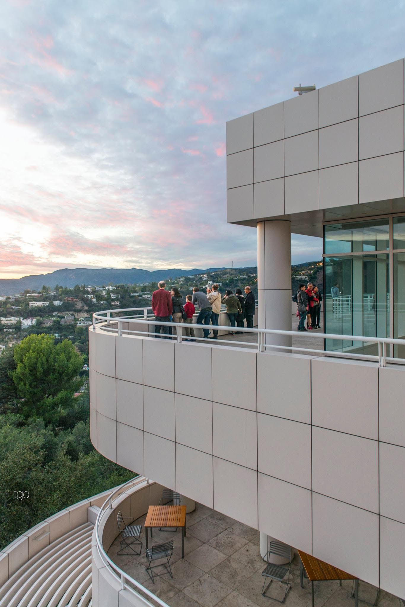 White cladding, a curved stair and visitors on a Getty Center terrace overlooking Los Angeles.