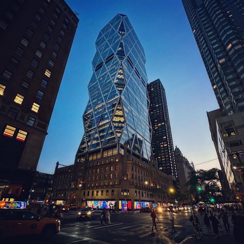 A glass tower with a diagonal structure above a busy Manhattan intersection.