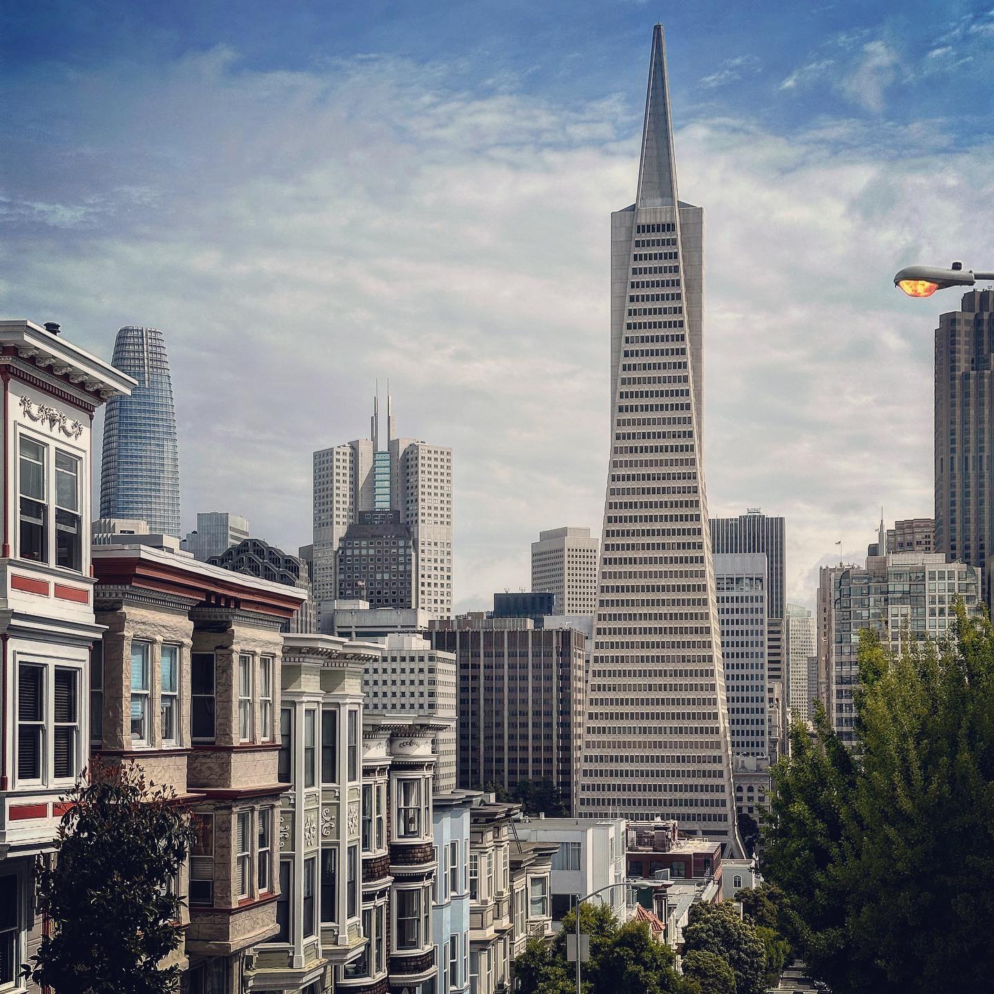 A pointed tower rises above a hillside of street façades.