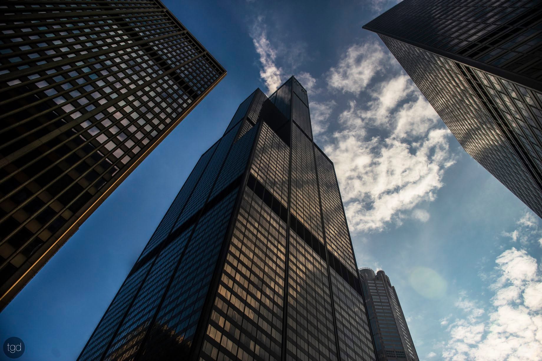 Willis Tower and neighbouring façades converge around an opening of blue sky.