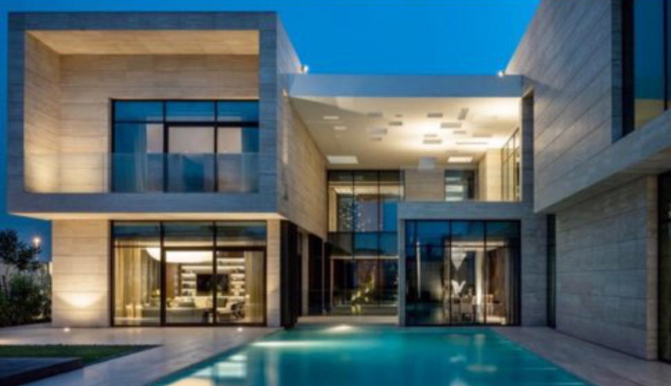 The villa illuminated beside its pool at dusk.